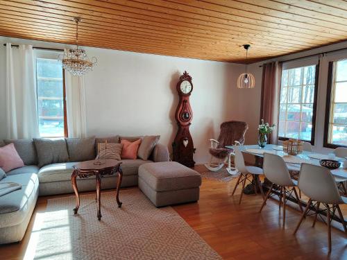 a living room with a couch and a table and a clock at Metsäranta in Kalajoki