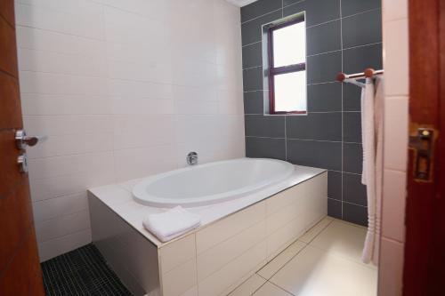 a white bath tub in a bathroom with a window at Tamboti Guest Lodge in Pretoria