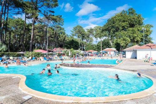 un groupe de personnes dans une piscine d'un complexe hôtelier dans l'établissement Bungalow-Mobilhome - Petit prix- Océan -Forêt -Camping 3 étoiles, à Bias