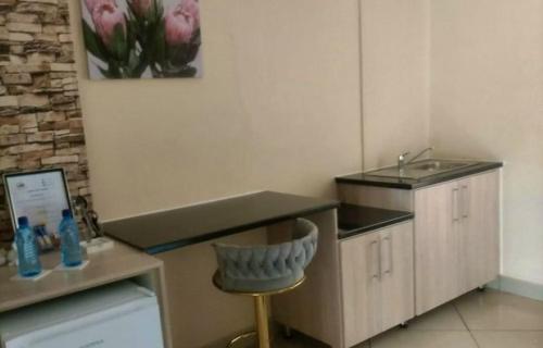 a small kitchen with a sink and a stool at C-rane guesthouse in Phalaborwa
