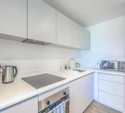 a white kitchen with white cabinets and a sink at Stunning Central Birmingham1 Bedroom Apartment in Birmingham