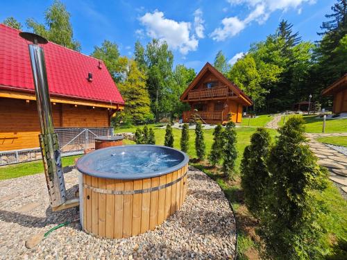 a hot tub in a yard next to a cabin at Górskie Wytchnienie Domki Karkonosze in Piechowice