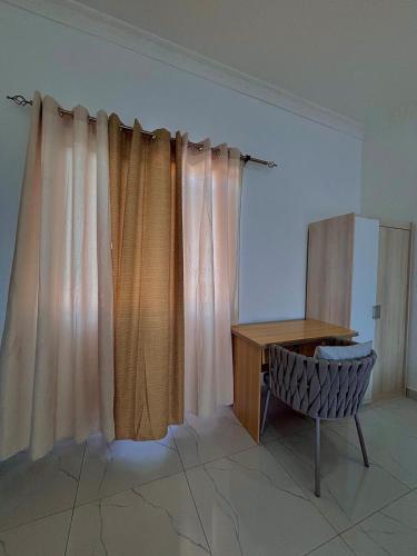 a room with curtains and a desk and a chair at Izire Home in Tokuse