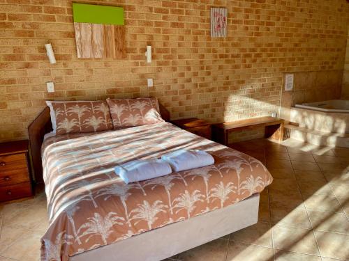 a bedroom with a bed with two pillows and a tub at Spring Bay Villas, Denmark, WA in Denmark