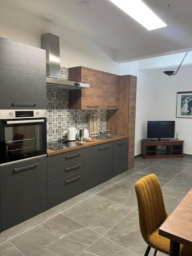 a kitchen with gray cabinets and a table and a dining room at 1bed Mel Apt W Church Views By Homely Malta! in Mellieħa