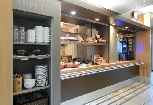 a display case in a restaurant with dishes at B&B HOTEL Alencon Nord in Alençon