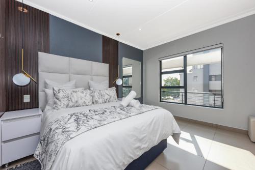 a bedroom with a large bed and a window at The Odyssey Lifestyle Complex Morningside - 2 BR in Johannesburg