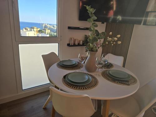 a dining room table with plates and a vase with flowers at Intercomercio Feja Jupiter in Benalmádena