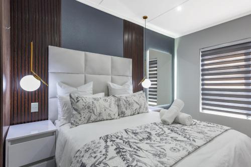 a bedroom with a large white bed with pillows at The Odyssey Lifestyle Complex Morningside - 2 BR in Johannesburg