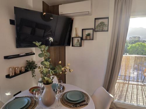 a dining room with a table with a tv on the wall at Intercomercio Feja Jupiter in Benalmádena