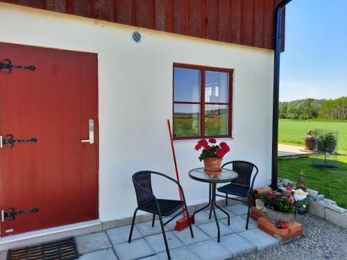 a patio with a table and chairs and a red door at Gårdslägenhet nära Göteborg in Alvhem