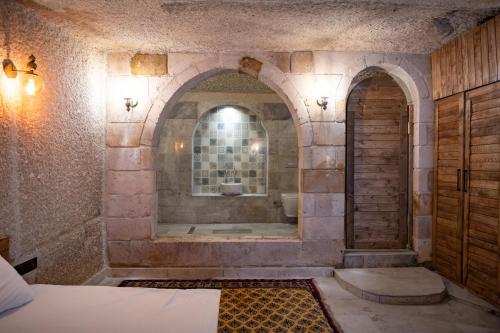 a bathroom with a tub in a stone wall at Gedik Cave Hotel in Goreme
