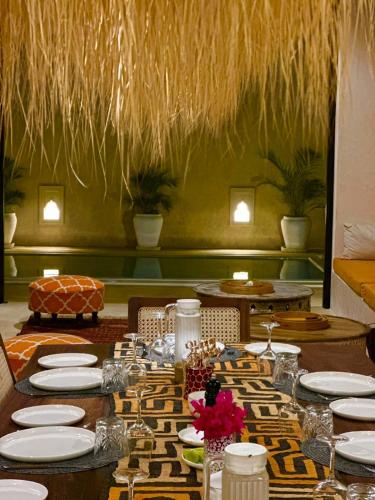 a dining room with a long table with white plates at Tulia House Lamu in Lamu