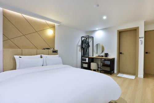 a white bedroom with a large bed and a desk at Brown Dot Gumi Okgye in Gumi