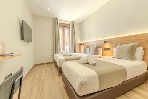 a hotel room with two beds and a television at Hotel La Milagrosa in Alicante