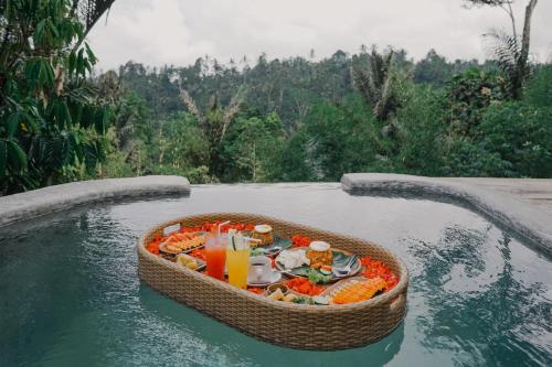 een dienblad met eten in een mandje in het water bij The Fire Flies Garden Villa in Penginyahan
