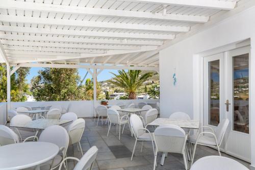 a restaurant with white tables and white chairs at Pyrgaki Hotel in Parikia
