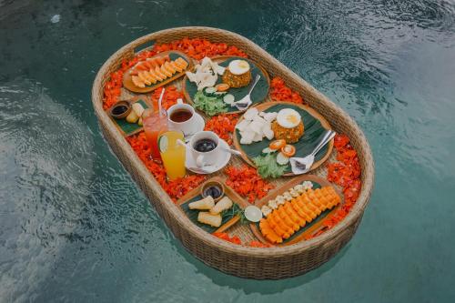 een kleine boot vol met voedsel op het water bij The Fire Flies Garden Villa in Penginyahan