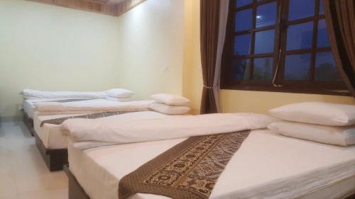 a group of three beds in a room with a window at Sa Pa Madame Huong Hotel in Sa Pa