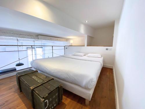 - une chambre avec un grand lit blanc et une grande fenêtre dans l'établissement Le Balthazar Beau T1 mezzanine, centre historique, à Montpellier