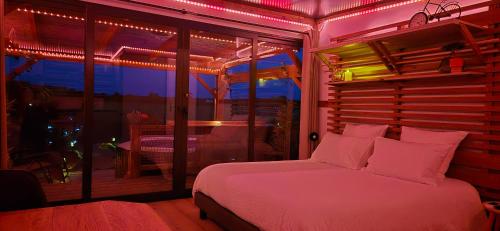 une chambre avec un lit avec des lumières roses dessus dans l'établissement La Luna - Tiny House Spa - Romantique & Nature, à Saint-Yan