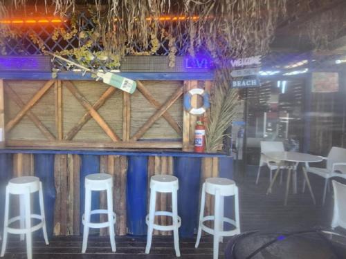 a bar with four white stools in a restaurant at Beach Island Graskop in Graskop