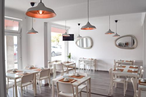 a restaurant with white tables and white chairs and lights at Residência Maciel in Peniche