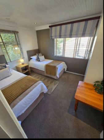 a hotel room with two beds and a window at Knysna River Club Getaways - Luxury waterfront chalets in Knysna