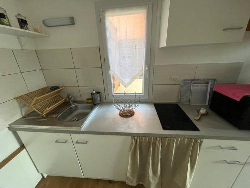 une petite cuisine avec un évier et une fenêtre dans l'établissement Pavillon Beau Soleil à Narbonne Plage, à Narbonne-Plage