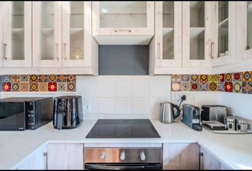 a kitchen with white cabinets and a stove top oven at Knysna River Club Getaways - Luxury waterfront chalets in Knysna