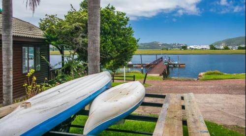 a canoe and a boat on a bench next to a lake at Knysna River Club Getaways - Luxury waterfront chalets in Knysna