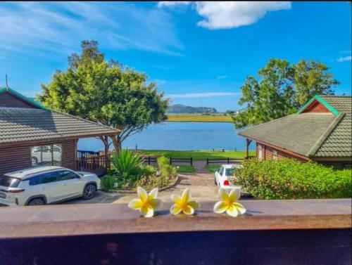 two cars parked in front of a house with flowers at Knysna River Club Getaways - Luxury waterfront chalets in Knysna