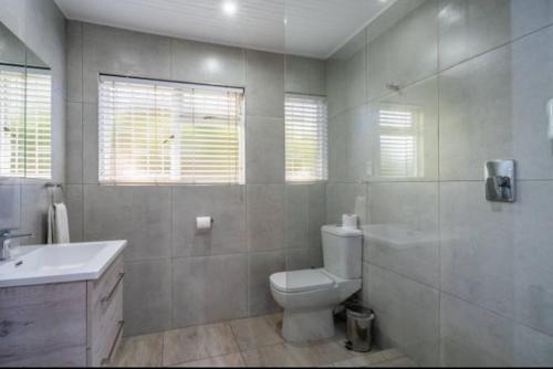 a white bathroom with a toilet and a sink at Knysna River Club Getaways - Luxury waterfront chalets in Knysna