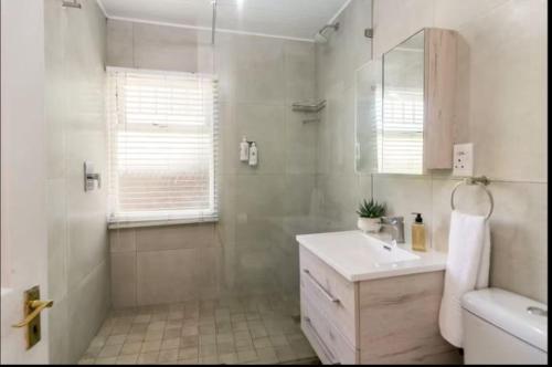 a white bathroom with a shower and a sink at Knysna River Club Getaways - Luxury waterfront chalets in Knysna