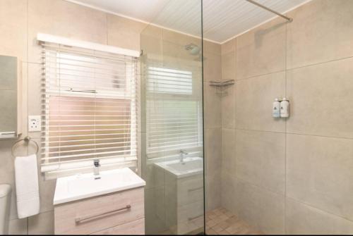 a bathroom with a sink and a glass shower at Knysna River Club Getaways - Luxury waterfront chalets in Knysna
