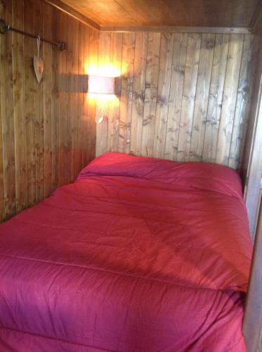 a red bed in a room with a wooden wall at Mon Bijou on the ski slopes in Sauze d'Oulx