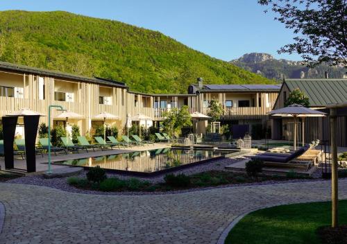a resort with a pool and chairs and a mountain at Agrad Chalets in Aschau im Chiemgau