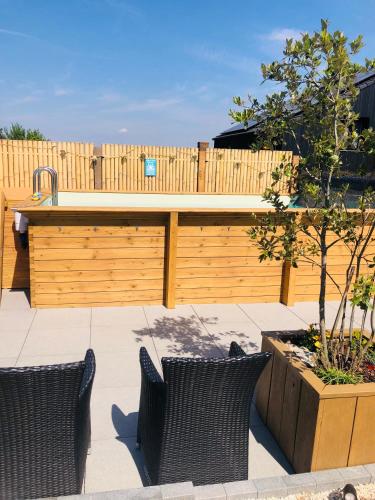 a patio with two wicker chairs in front of a wooden fence at Privé Glamping & wellness Moonlight in Brakel