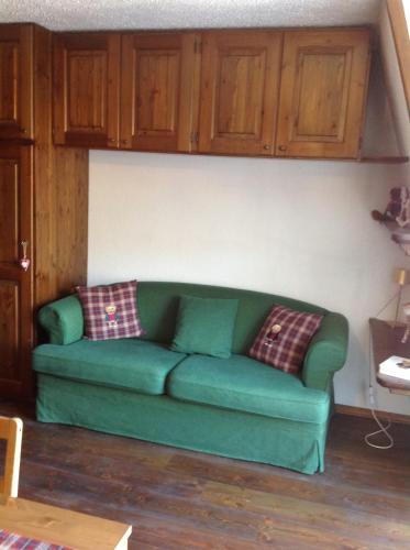 a green couch in a living room with wooden cabinets at Mon Bijou on the ski slopes in Sauze d'Oulx