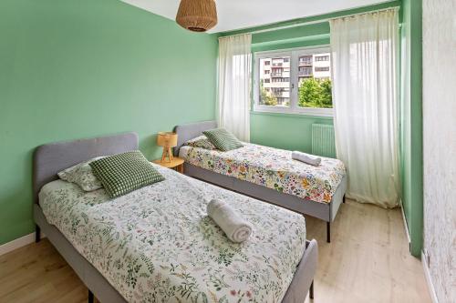 deux lits dans une chambre avec des murs verts et une fenêtre dans l'établissement Le Lagon - 10 min aéroport et de Nantes, à Rezé