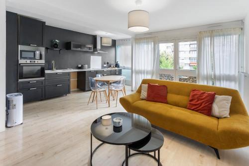 un salon avec un canapé jaune et une table dans l'établissement Le Lagon - 10 min aéroport et de Nantes, à Rezé