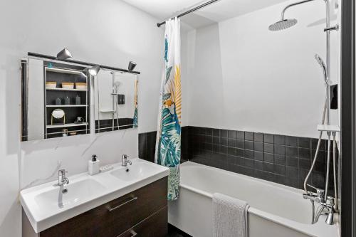 une salle de bain avec un lavabo, une baignoire et un miroir dans l'établissement Le Lagon - 10 min aéroport et de Nantes, à Rezé