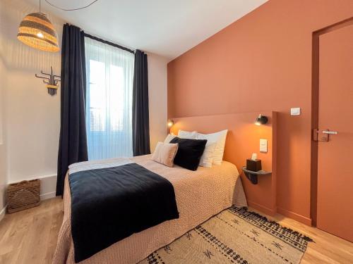 a bedroom with a bed with orange walls and a window at Hôtel du Commerce in Cluny