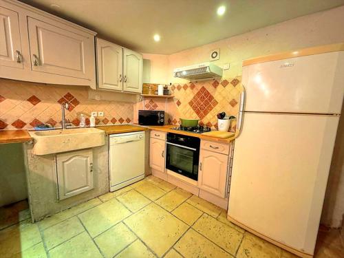 a kitchen with white appliances and a white refrigerator at Spacieuse maison de village, centre de Lorgues in Lorgues