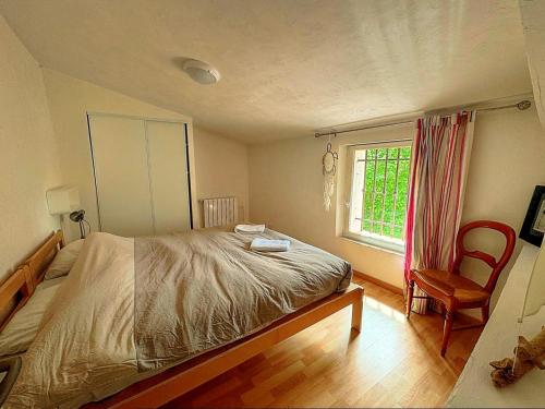 a bedroom with a bed and a chair and a window at Spacieuse maison de village, centre de Lorgues in Lorgues