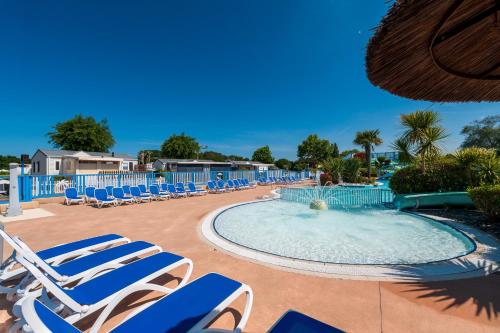 une piscine avec des chaises longues et une piscine dans l'établissement Mobilhome - Piscine - Premium, à Erdeven