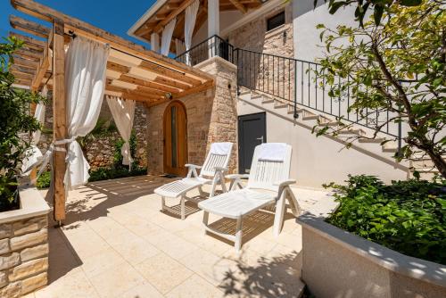 a patio with two chairs and a staircase at Apartment Varos with shared pool in Ugljan