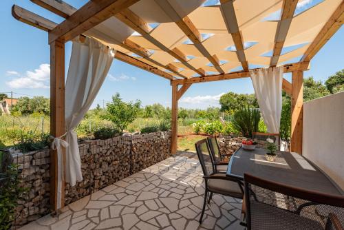 a patio with a table and chairs under a wooden pergola at Apartment Varos with shared pool in Ugljan