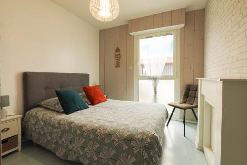 a bedroom with a bed with colorful pillows on it at Superbe appart.55m2 - 200m Ocean et parking in Biscarrosse