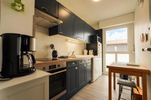 - une cuisine avec des placards noirs, un évier et une table dans l'établissement Superbe appart.55m2 - 200m Ocean et parking, à Biscarrosse